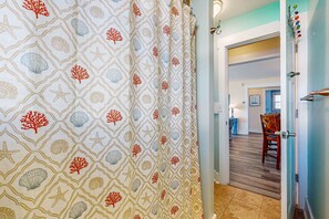 Un couloir avec un rideau à motifs, une porte en bois et, au fond, un coin repas.