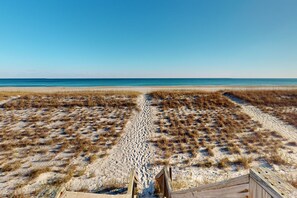 Een strand met een houten looppad dat naar het water leidt.