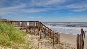 Una passerella in legno che conduce a una spiaggia con le onde che si infrangono sulla riva.