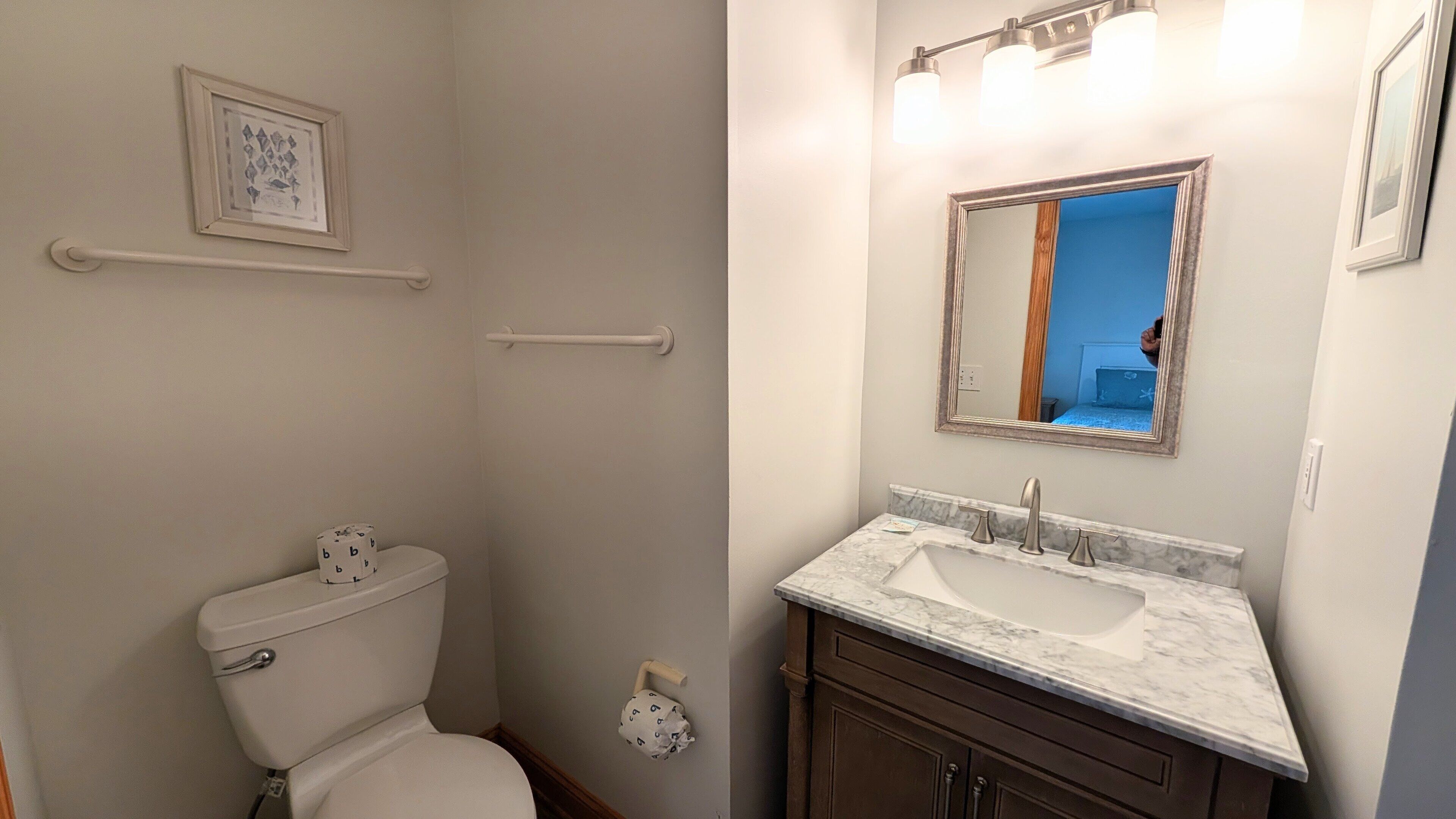 Een badkamer met toilet, wastafel, spiegel en handdoekhouder.