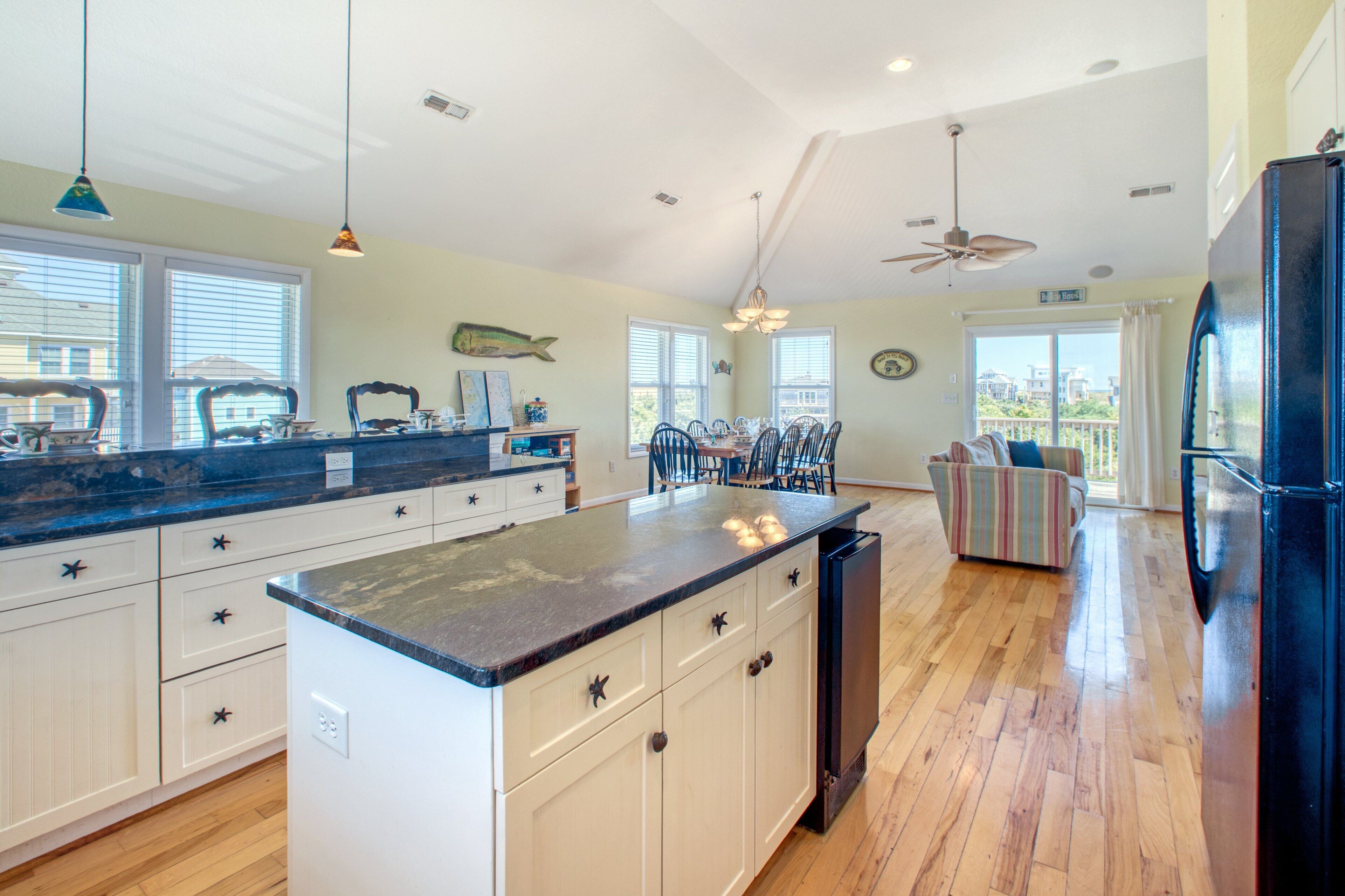 A spacious kitchen with a large island, white cabinetry, and a black refrigerator.