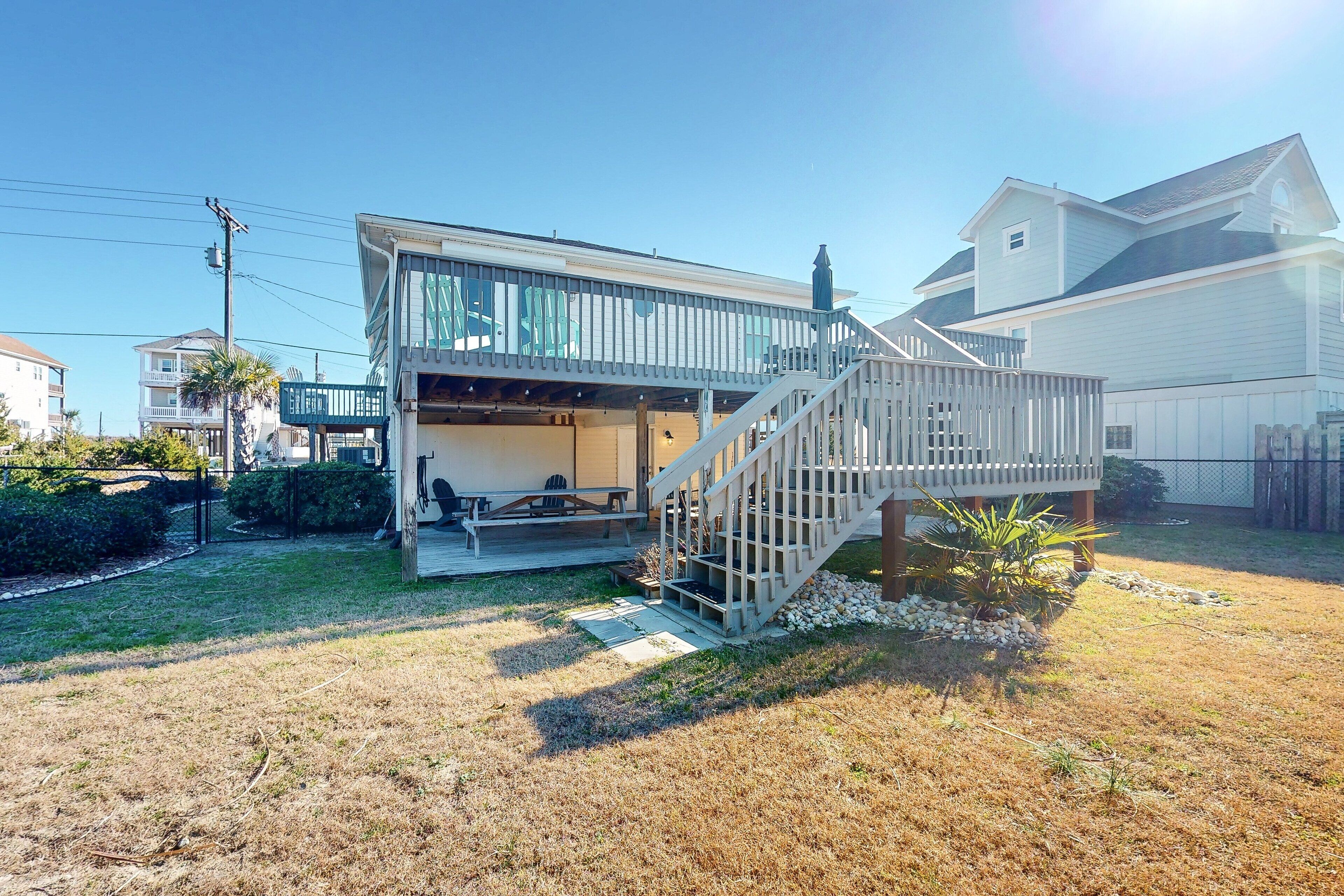 A house with a covered patio, a staircase, and a small garden area.