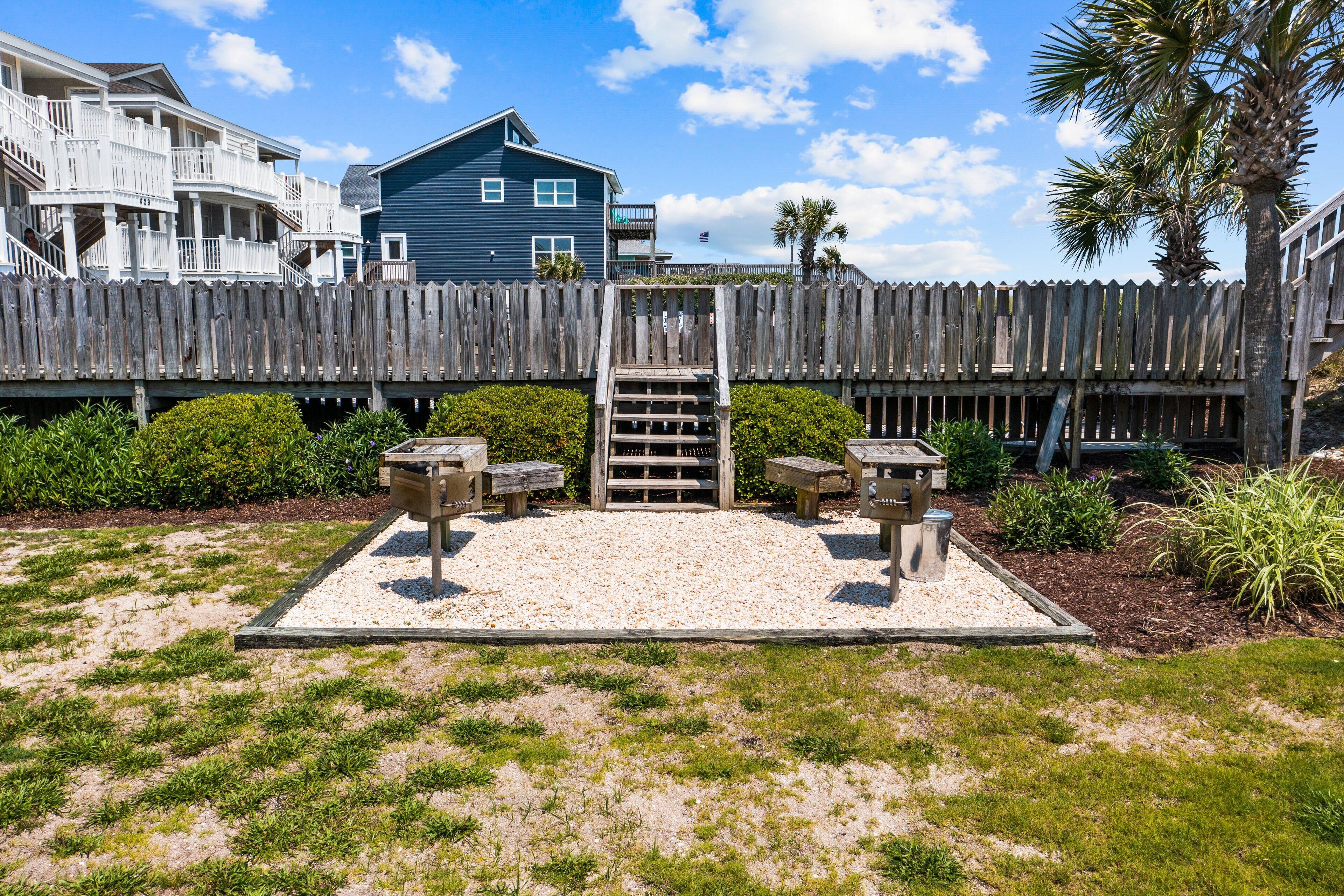 A wooden deck with a staircase leading to a deck chair area, surrounded by a wooden fence and a house in the background.