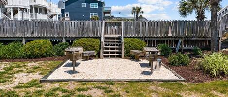 A wooden deck with a staircase leading to a deck chair area, surrounded by a wooden fence and a house in the background.
