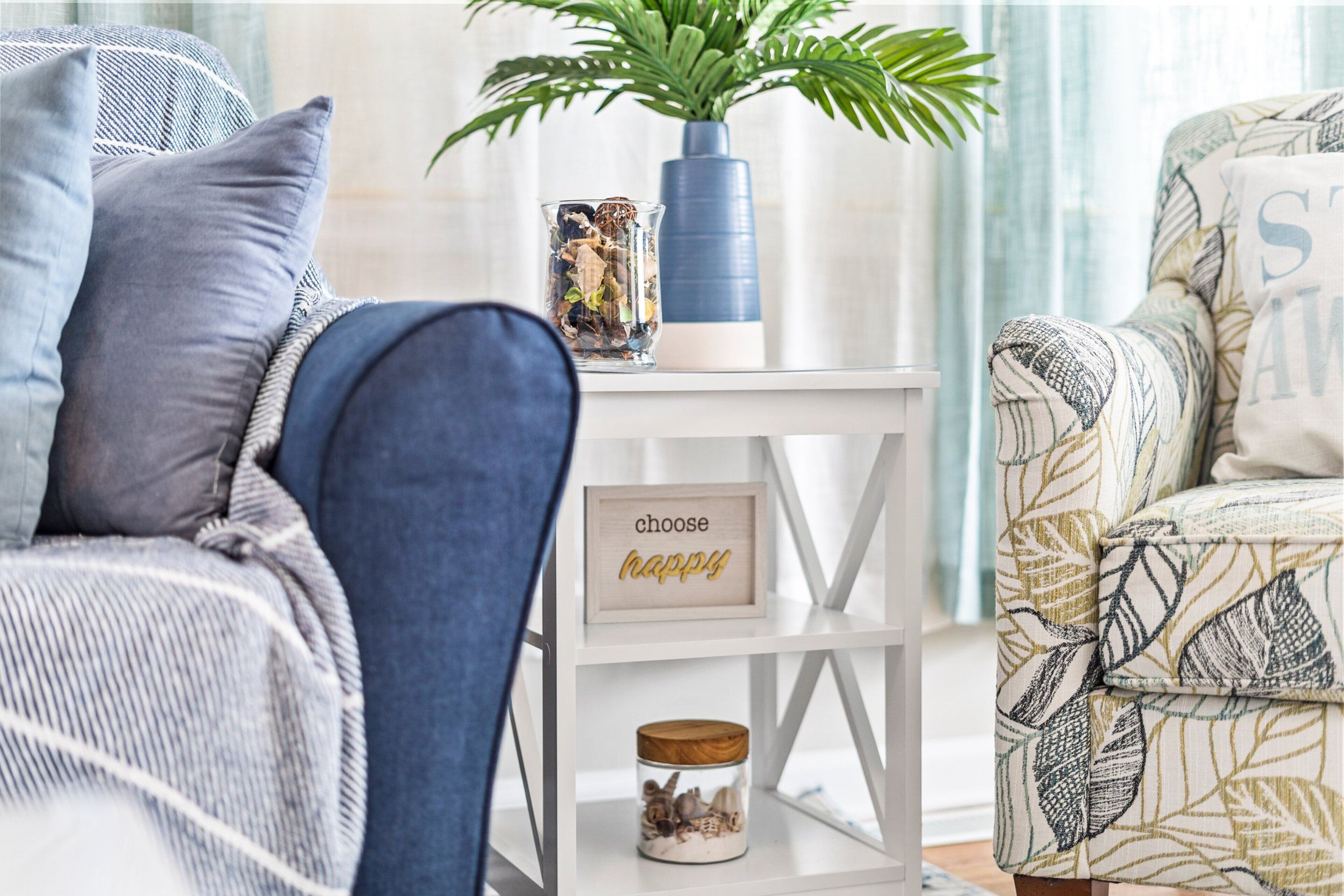 A living room with a sofa, a side table with decorative items, and a chair.