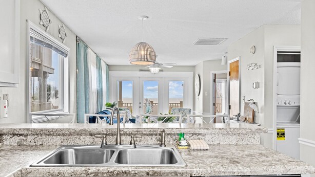 A modern kitchen with granite countertops, stainless steel appliances, and large windows offering views of the outdoors.