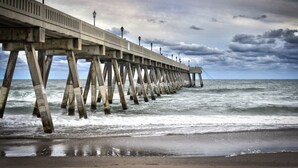 A pier extending into the sea with a cloudy sky above.