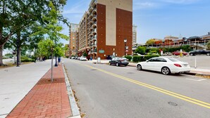 A multi-story hotel with a prominent vertical design element, a brick facade, and a parking lot with several cars.