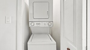 Et lille, hvidt vaskerum med vaskemaskine og tørretumbler stablet oven på hinanden.