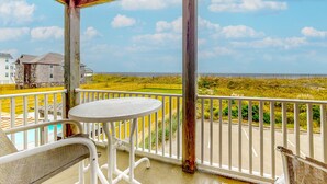 A balcony with a table and chairs, overlooking a landscaped area and a distant building.