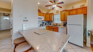A kitchen with wooden cabinets, a white refrigerator, a microwave, and a ceiling fan.