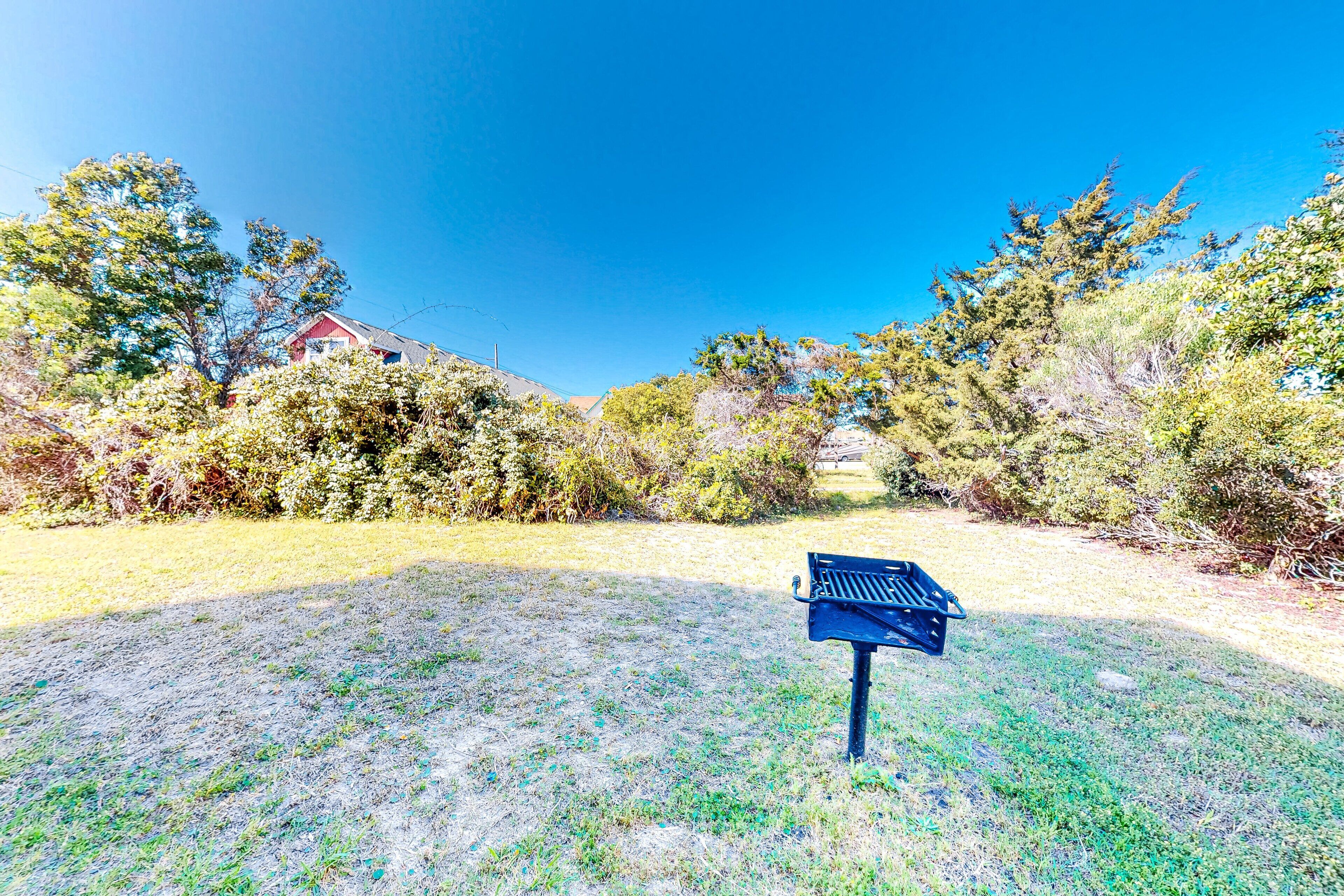 A grassy area with a blue bench and a red building in the background.