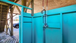 A turquoise bathroom with a shower, wooden ceiling, and a view of a parked car outside. - Forever June 383: Near the beach w/deck! (Avon)