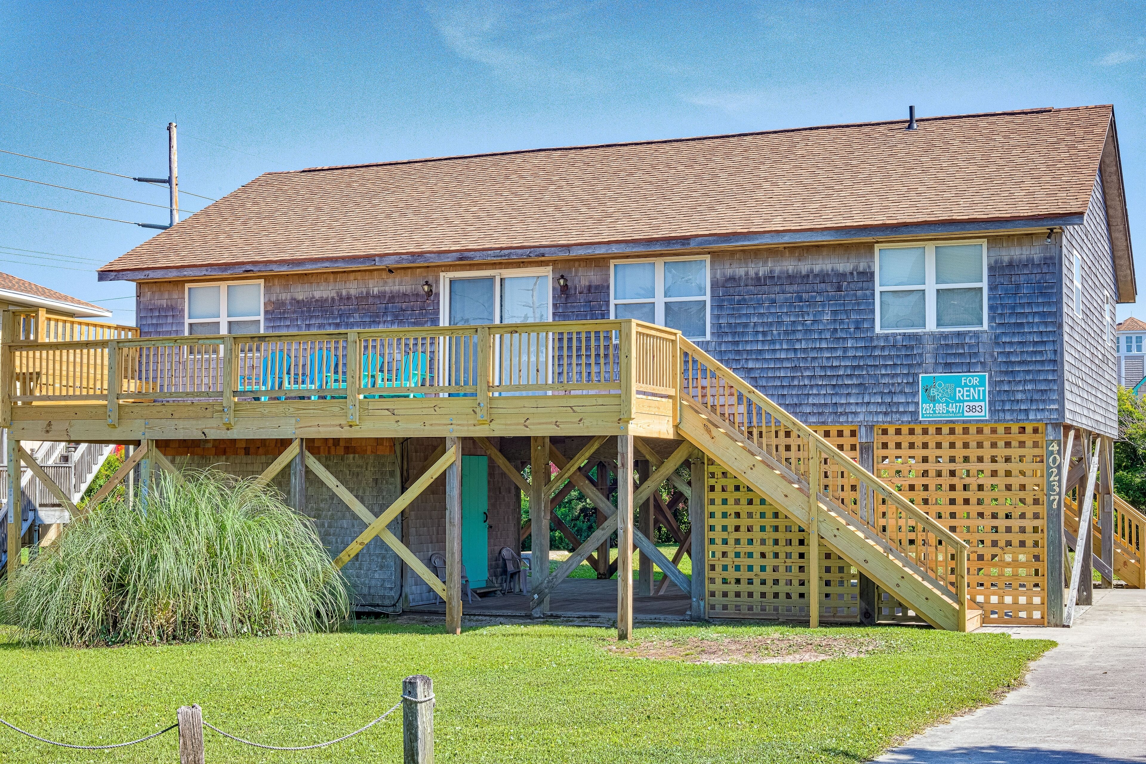 A two-story house with a wooden deck and a small porch.