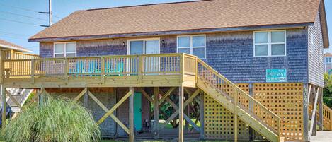 A two-story house with a wooden deck and a small porch.
