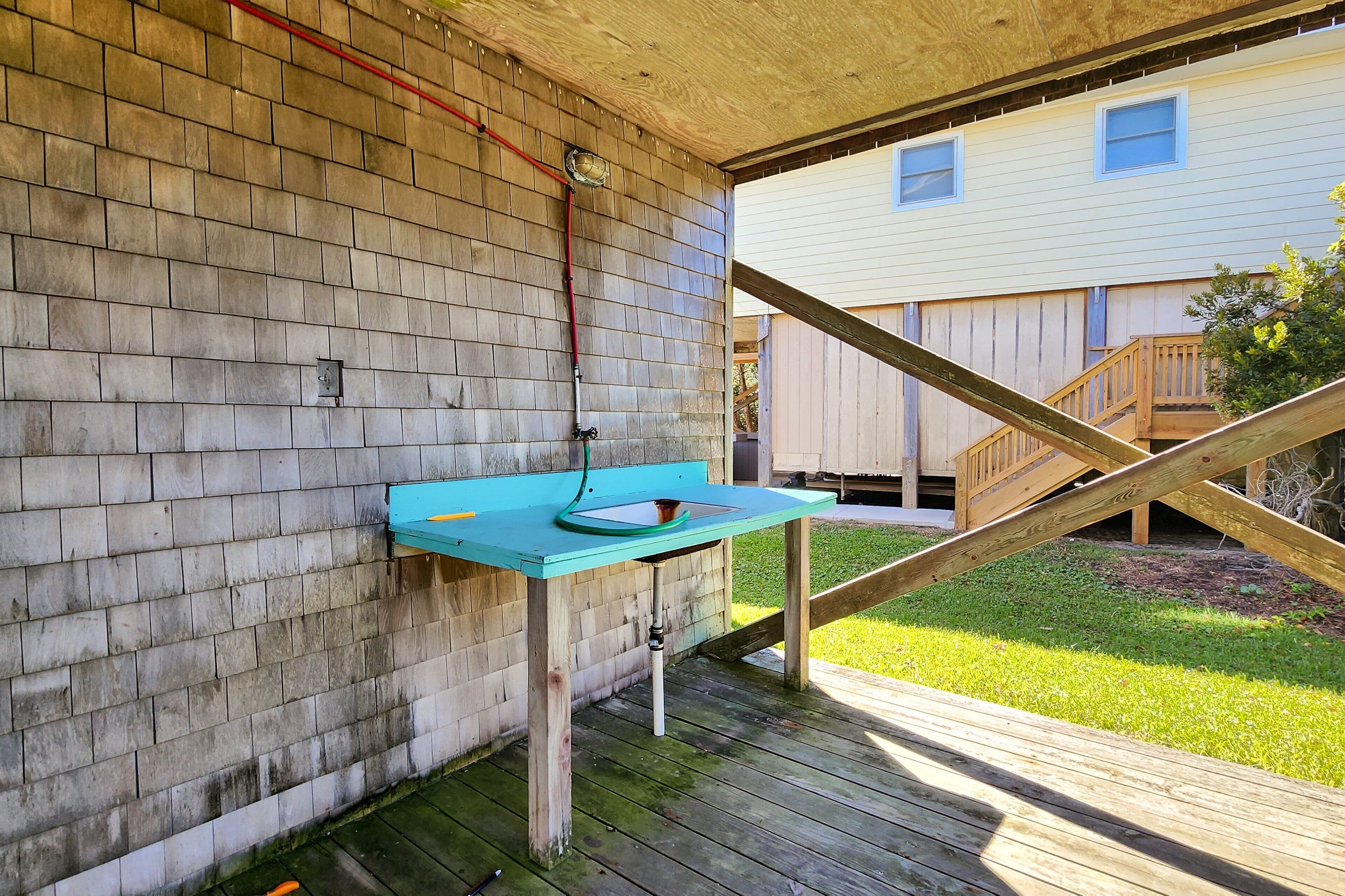 A wooden deck with a blue table and a metal sink.