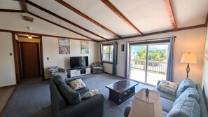 Ein Wohnzimmer mit einer Couch, einem Couchtisch, einem Fernseher und einem Balkon mit Blick.