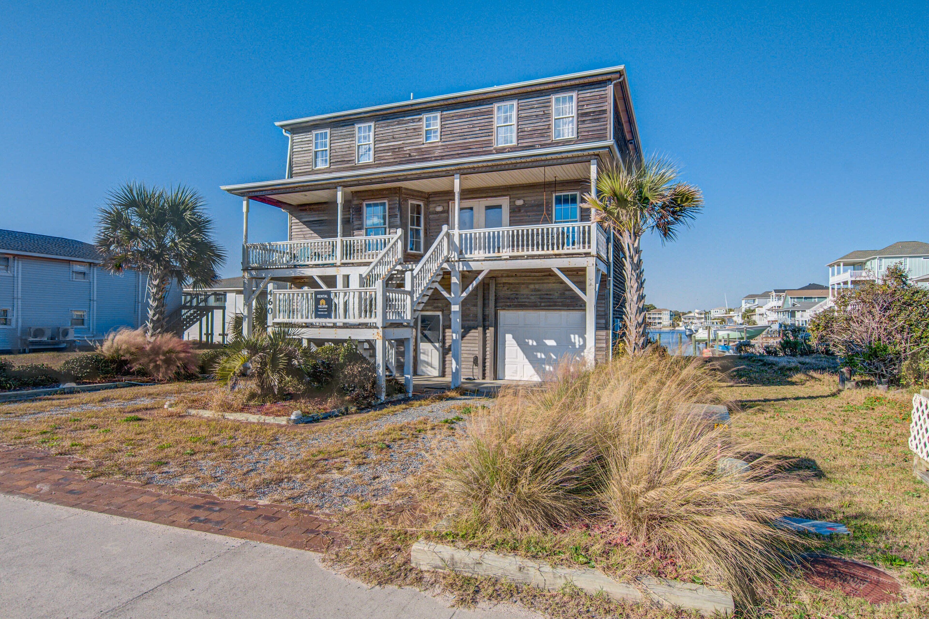 A two-story house with a balcony, a garage, and a well-maintained lawn.