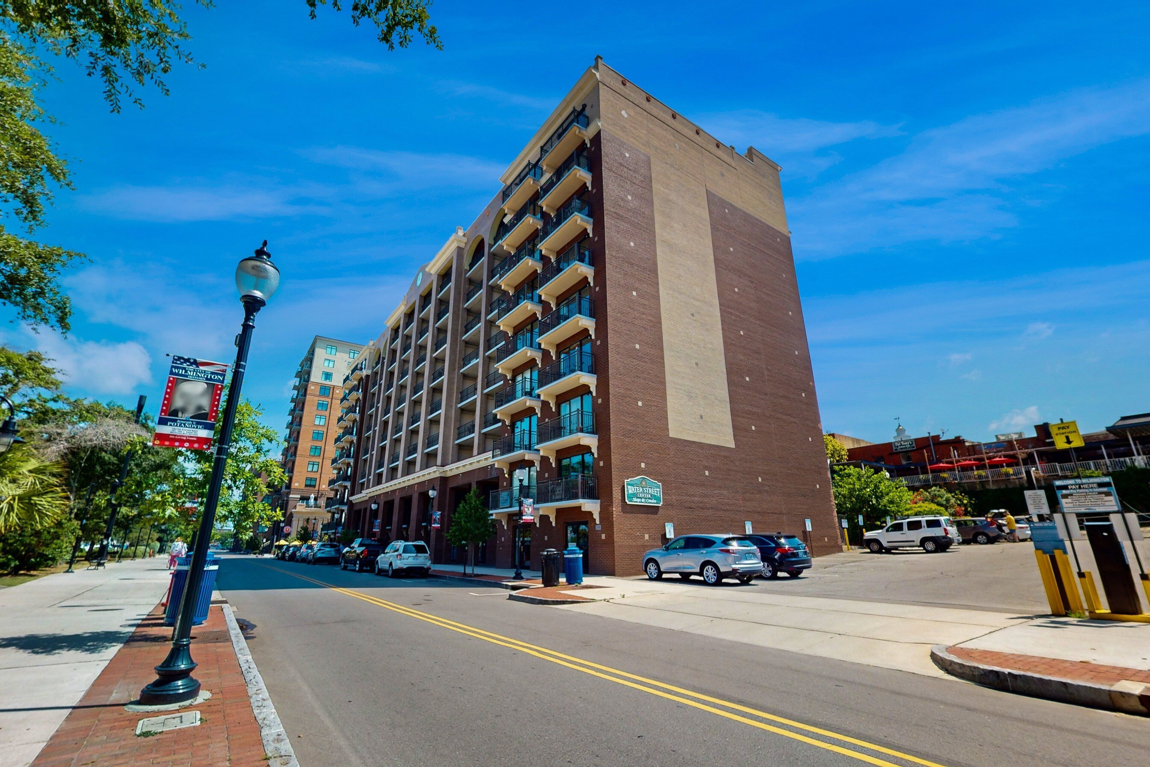 A multi-story hotel with a brick facade, balconies, and a clear blue sky.