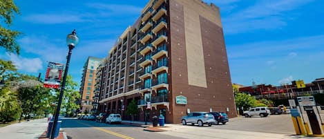A multi-story hotel with a brick facade, balconies, and a clear blue sky.