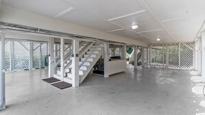 A spacious indoor area with a white staircase leading to a reception desk, surrounded by white lattice panels. - Oceanfront home with WiFi, central AC, washer/dryer  - dogs welcome (Holden Beach)