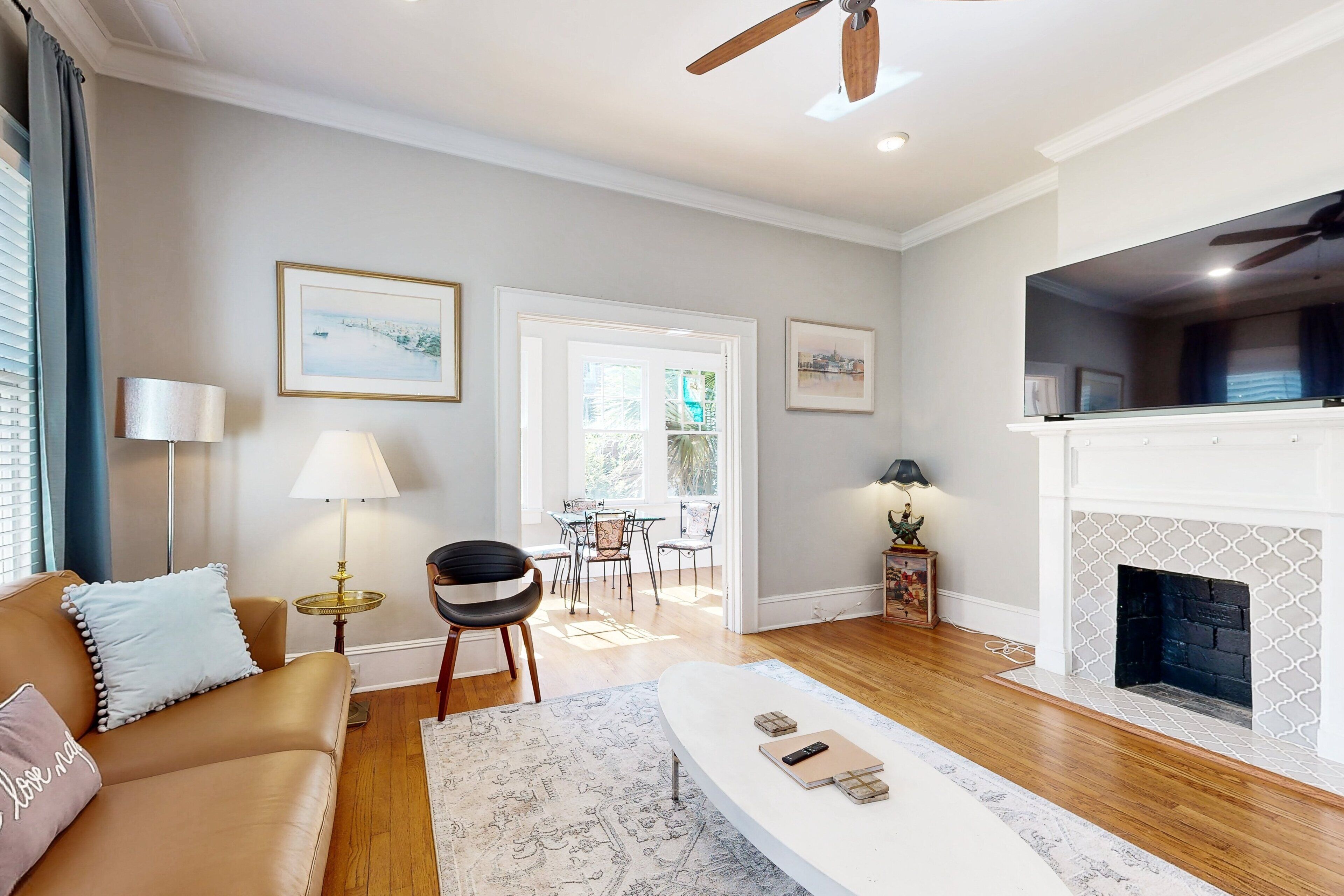 A living room with a sofa, coffee table, fireplace, and a dining area with chairs and a table.