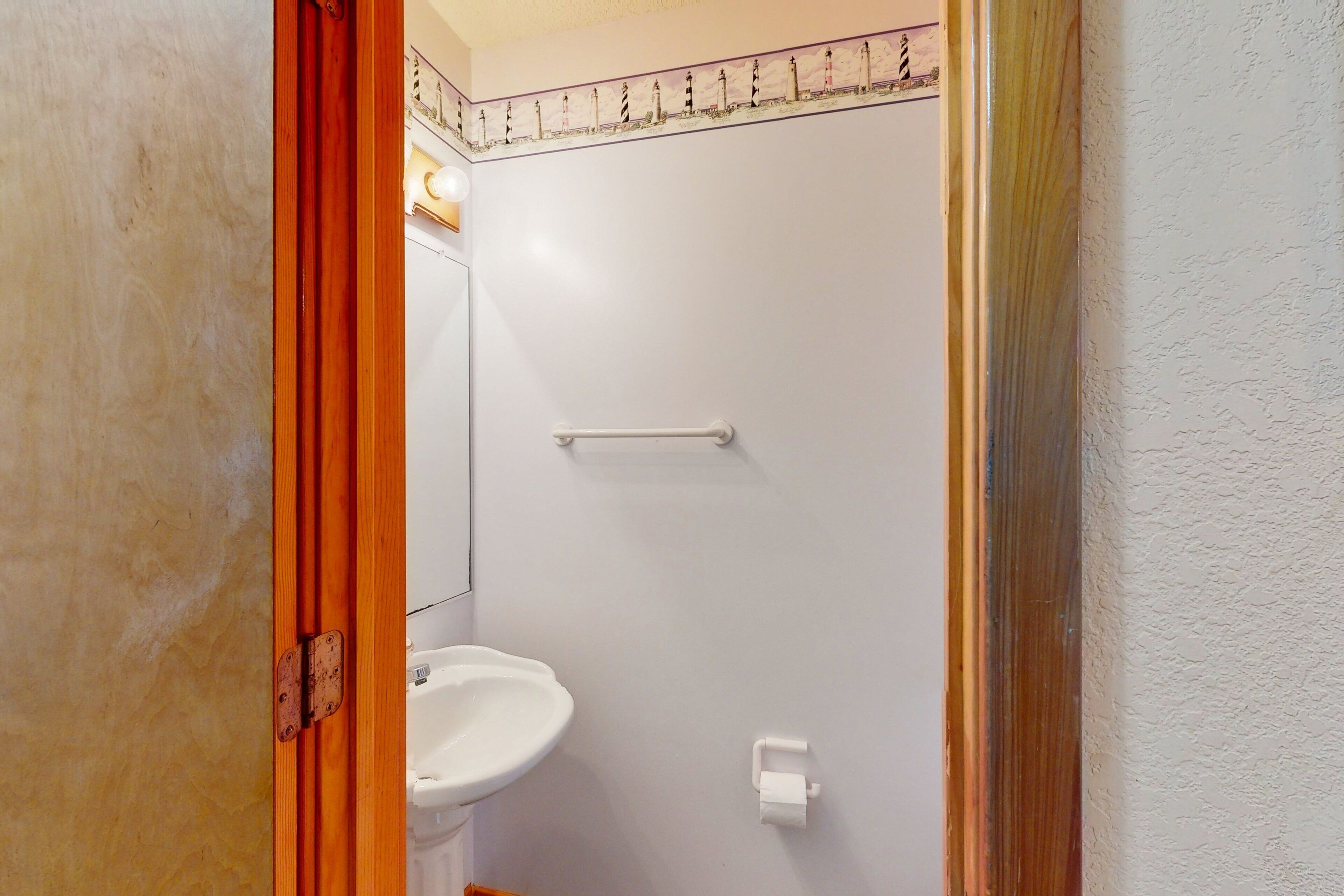 Un baño con un lavamanos blanco, un toallero y un dispensador de papel higiénico.