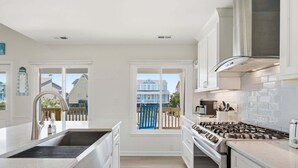 Una cocina moderna con una isla grande, horno integrado y vista al vecindario.