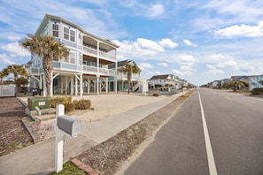 A coastal building with multiple balconies, a sidewalk, and a clear sky.