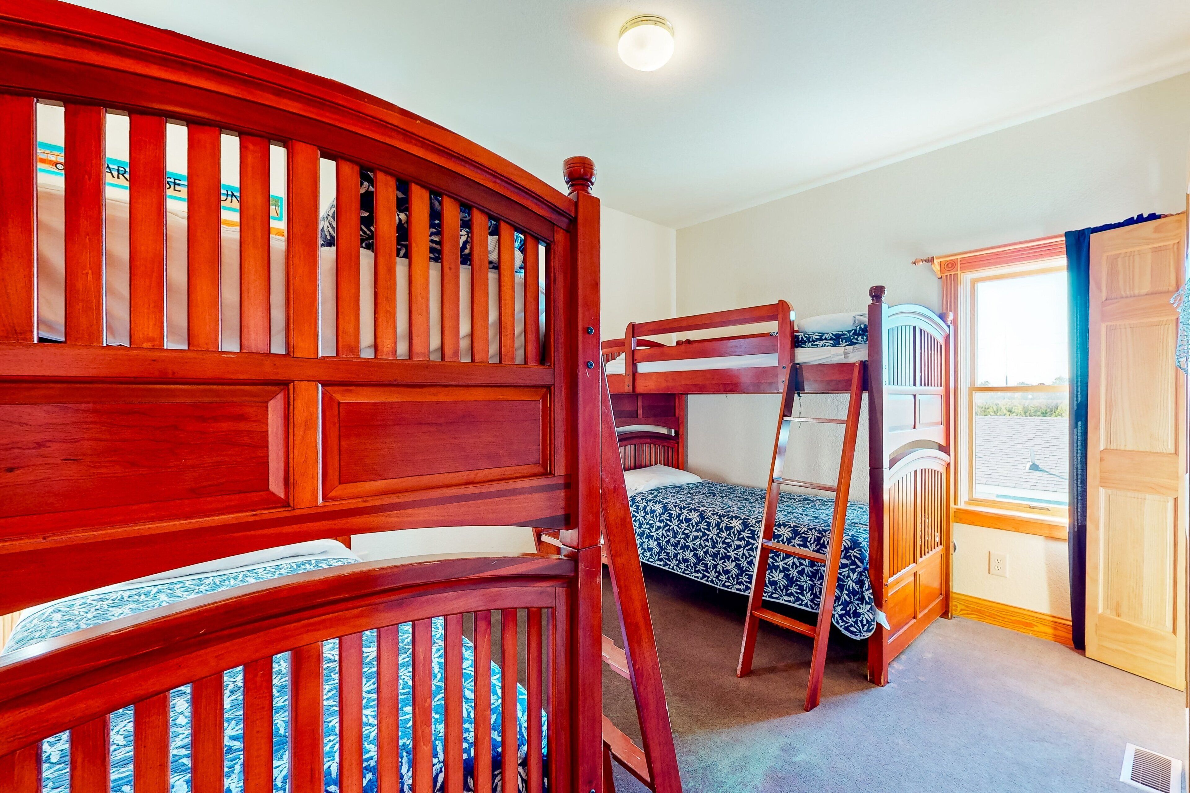 A room with bunk beds, a window with curtains, and a door.