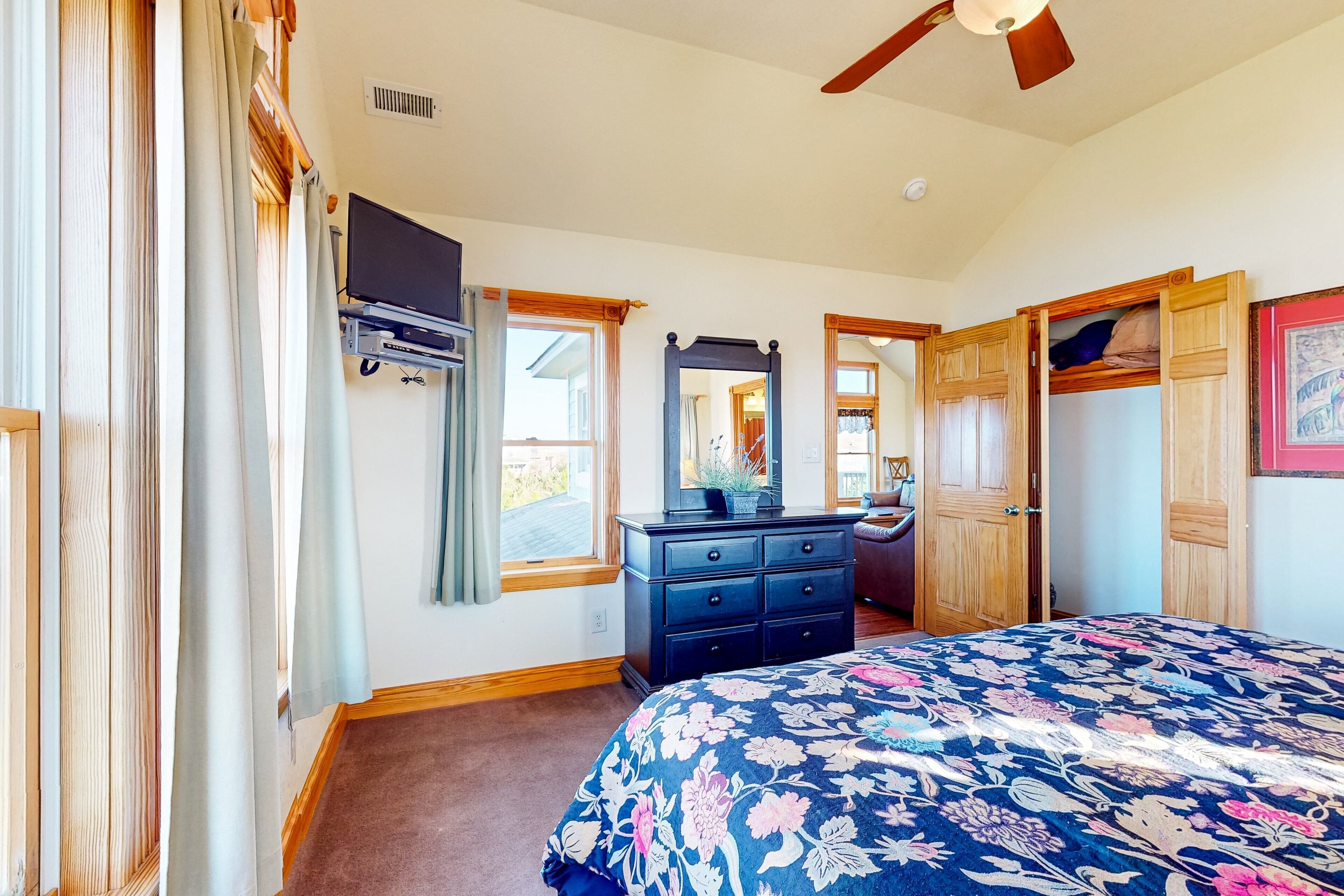 A bedroom with a bed, dresser, mirror, and a ceiling fan.