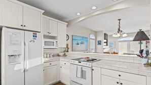 A kitchen with white cabinetry, a refrigerator, a microwave, an oven, and a sink. - Turtle's Watch: Canal-front dog-friendly home near beach, canal view, & dock (Holden Beach)