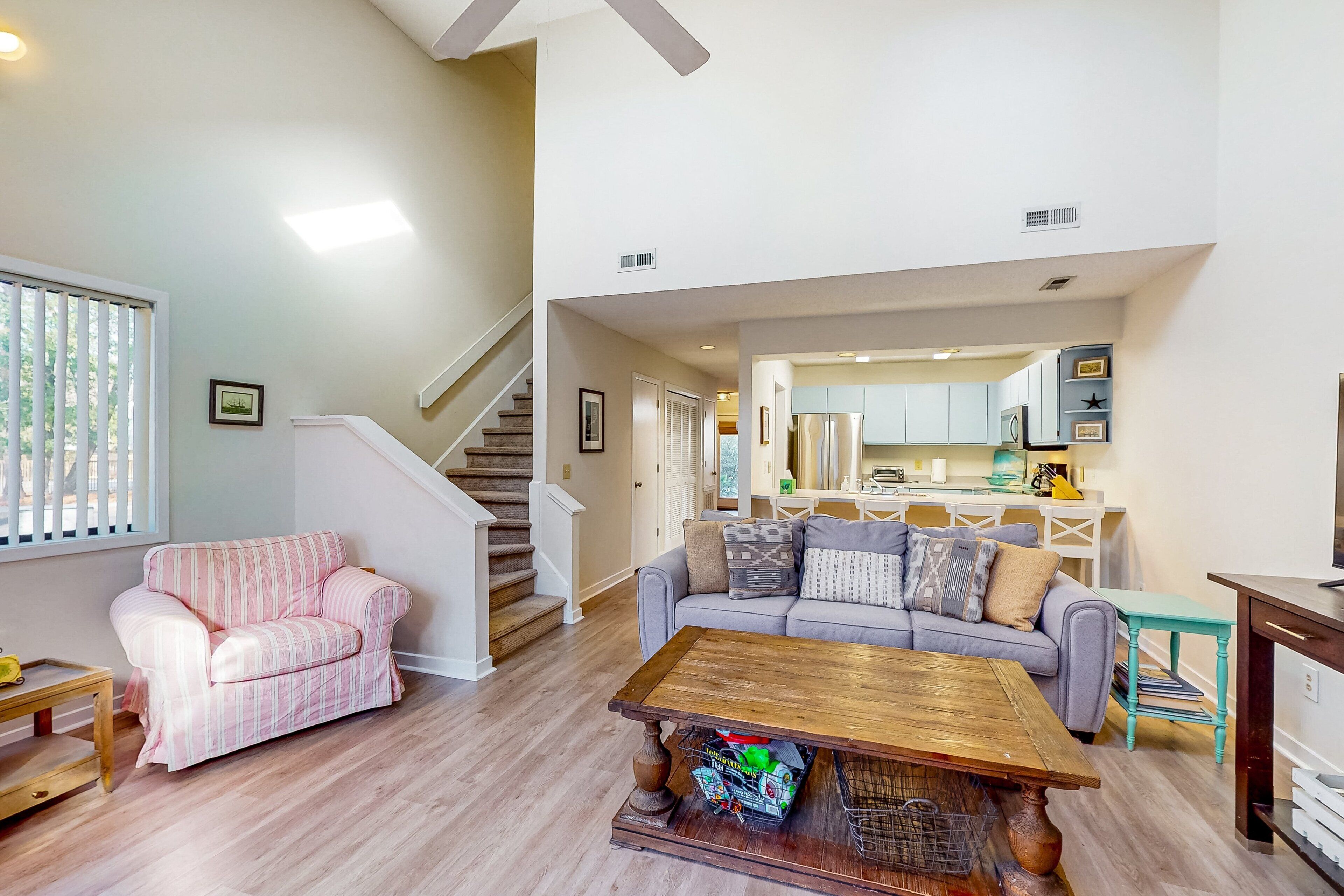 A spacious living room with a staircase, a kitchen area, and a dining space.