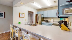 Una cocina moderna con una isla central, sillas blancas y un fregadero.