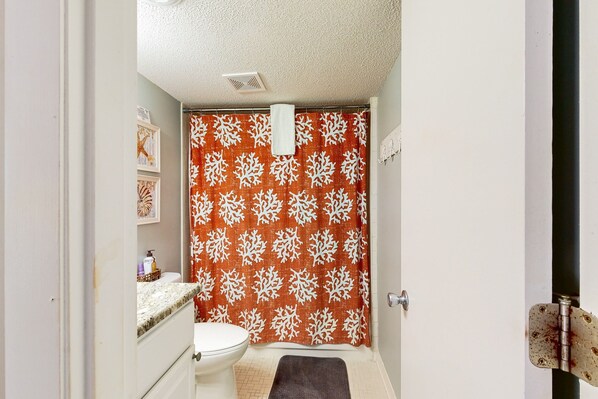 A bathroom with a toilet, a sink, and a shower curtain with a leaf pattern.