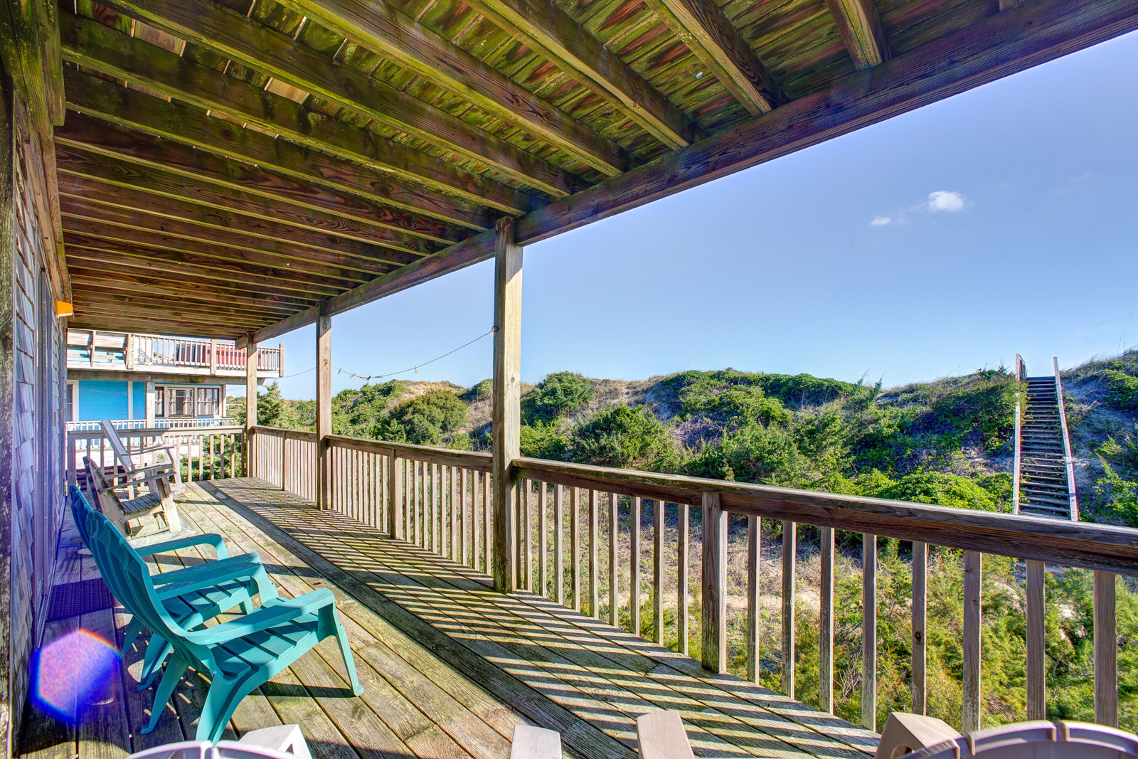 Une terrasse en bois, agrémentée de chaises, qui offre une vue sur un paysage montagneux.