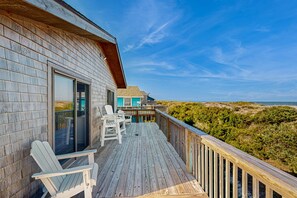 A wooden deck with a view of the beach and dunes.