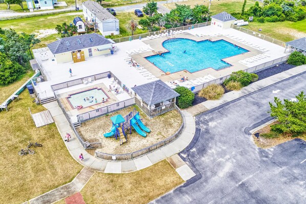 An aerial view of a residential area with a swimming pool, a playground, and a covered patio area.