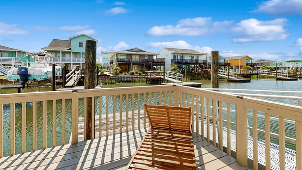 Ein Haus am Wasser mit einer Holzterrasse, einer Bank und Blick auf Häuser und Wasser.
