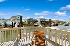 Ein Haus am Wasser mit einer Holzterrasse, einer Bank und Blick auf Häuser und Wasser.