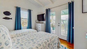 Ein Schlafzimmer mit zwei Betten, einem Fernseher und einem Balkon mit Blick.