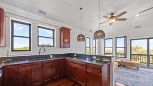 A spacious kitchen with wooden cabinets, a large island, pendant lights, and a ceiling fan. - Perfect Retreat with Private Hot Tub, Panoramic Views, Full Kitchen pet-friendly (Buxton)