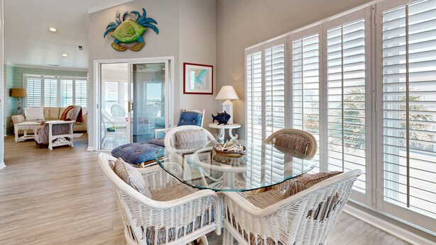 A spacious living area with wicker furniture, a glass-top coffee table, and large windows with blinds. - Dog-friendly marsh view home with large deck, close to beach access (Holden Beach)