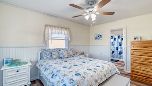 A bedroom with a bed, a nightstand, a dresser, and a ceiling fan.