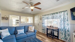 A living room with a blue sofa, a wooden coffee table, and a ceiling fan.