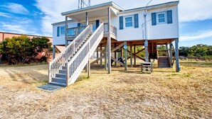 A two-story house with a wooden deck and a staircase leading to the upper floor.