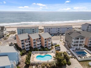 A beachfront hotel with multiple-story buildings, a swimming pool, and a beach view.