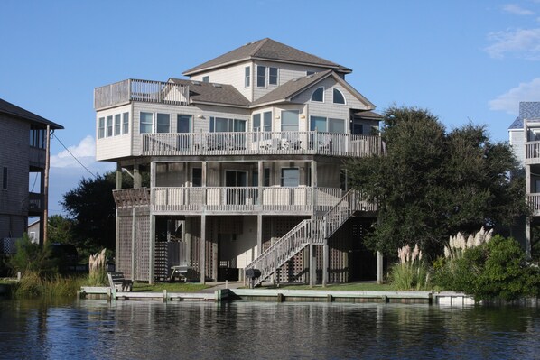A multi-story waterfront house with a balcony, a covered deck, and a staircase leading to the upper levels. - Waterfront House w/ Private Hot Tub, Free WiFi, Water View, Shared Pool (Frisco)