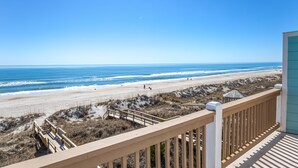 A beach view from a wooden deck with a clear sky. - Elegant beachfront escape with private boardwalk, free WiFi, & furnished balcony (Carolina Beach)