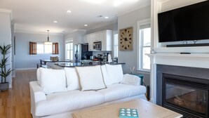 A modern living room with a white sofa, a coffee table, and a fireplace. - Elegant beachfront escape with private boardwalk, free WiFi, & furnished balcony (Carolina Beach)